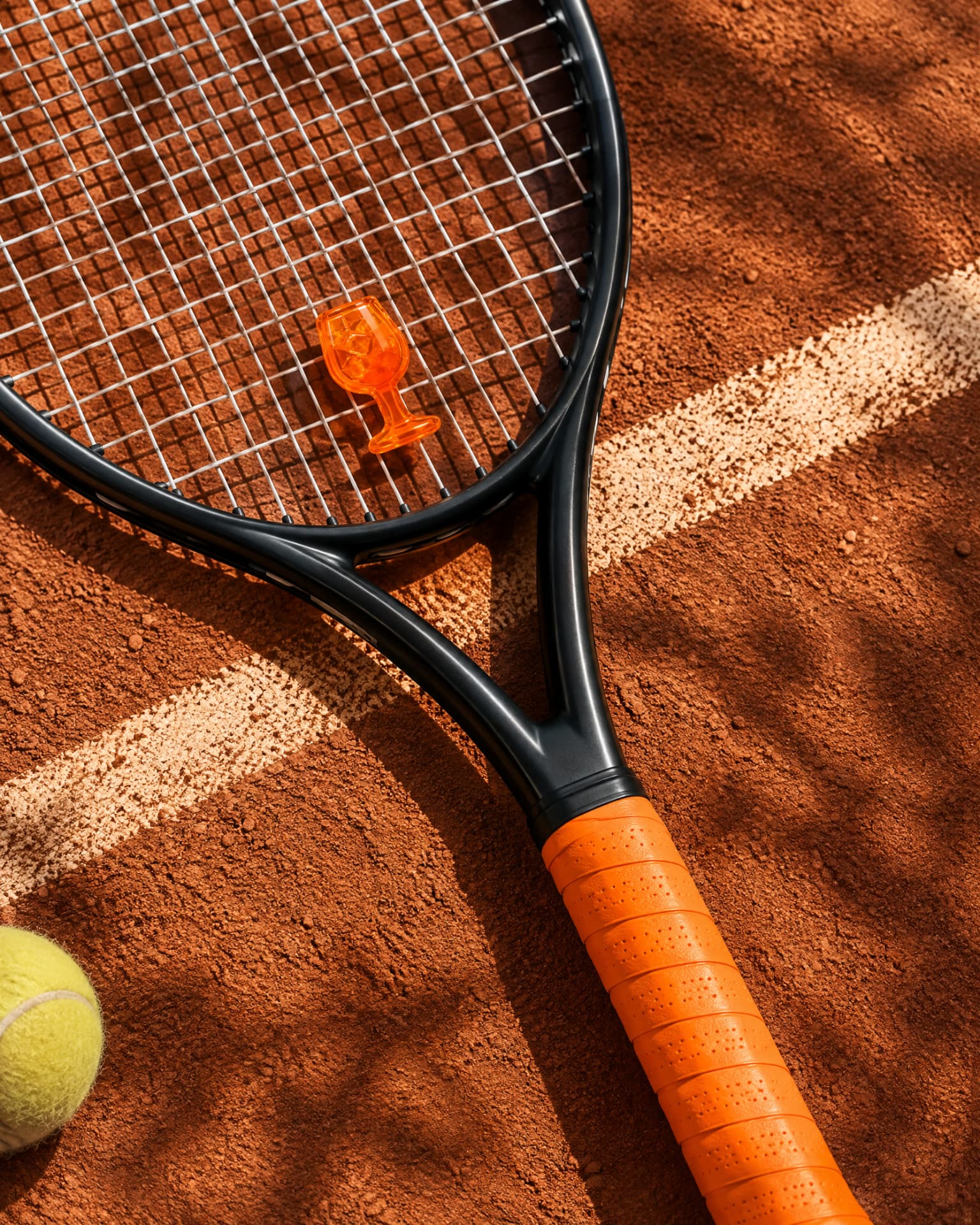 Aperol Spritz demper met oranje overgrip op een tennisracket